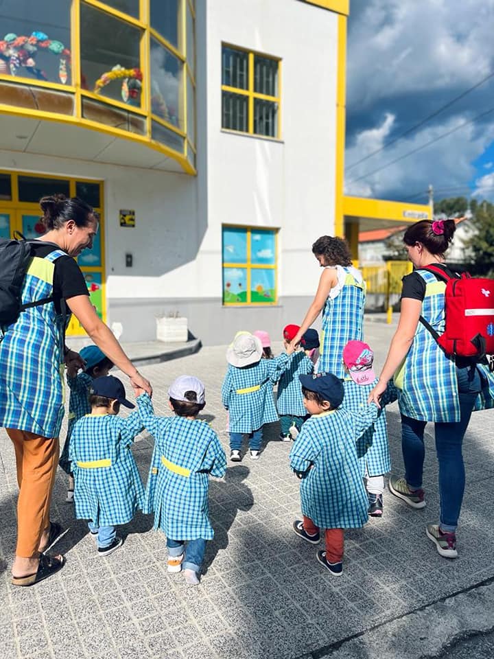 Crianças e educadora à entrada do Colégio Os Traquinas